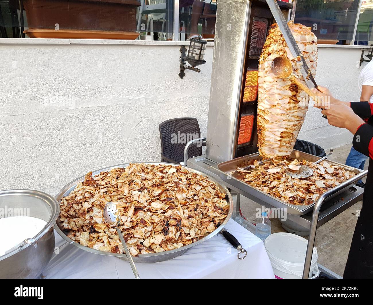 Ein Koch schneidet Hühnerfleisch auf einem Spieß, um Shawarma zu kochen. Traditionelles türkisches Essen Döner Kebab. Fast-Street-Food Stockfoto