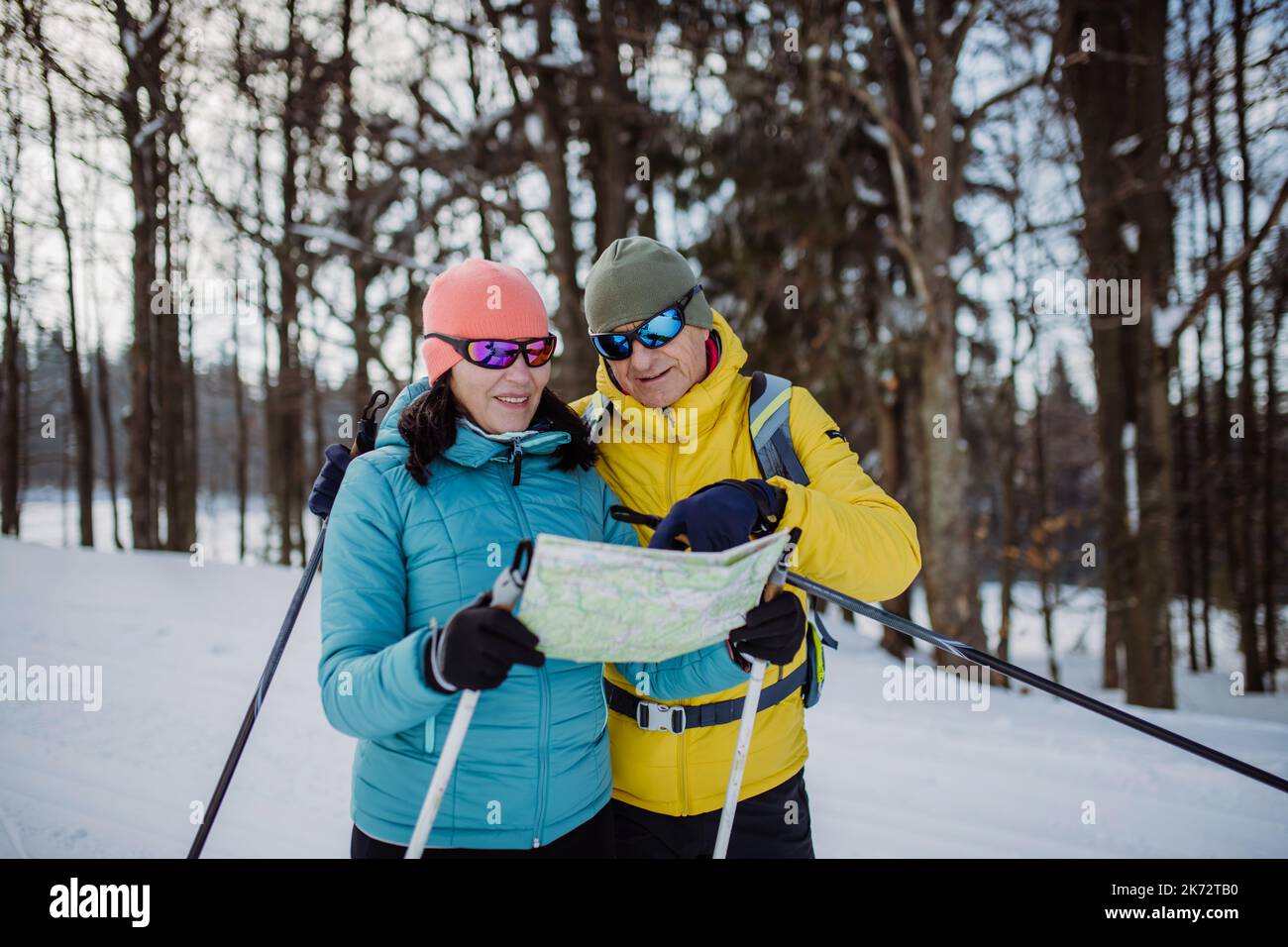 Ältere Paare, die sich während des Skilanglaufs im verschneiten Wald eine Karte ansehen. Stockfoto