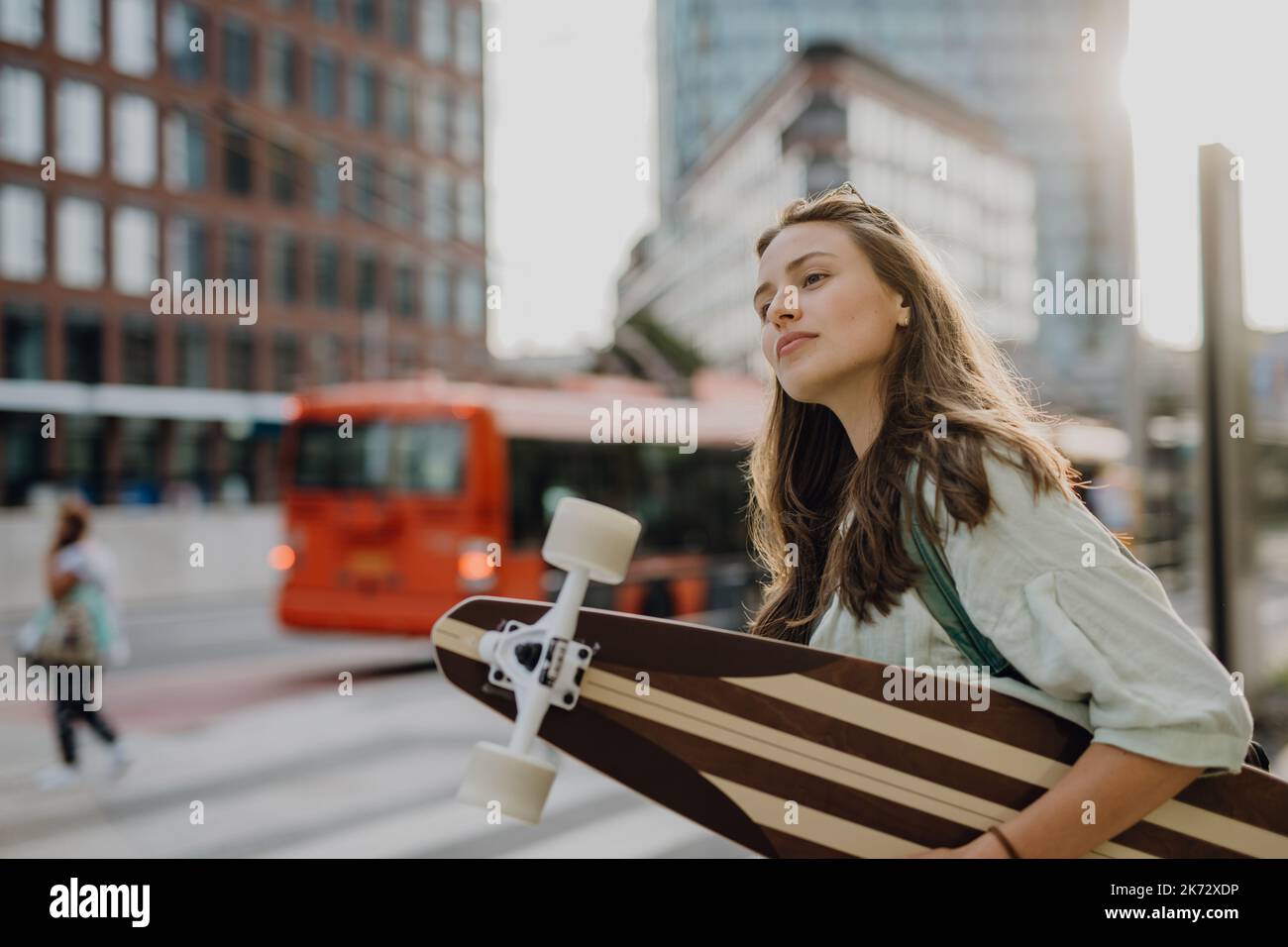 Junge Frau, die mit Skateboard in der Stadt läuft. Jugendkultur und Pendelkonzept. Stockfoto