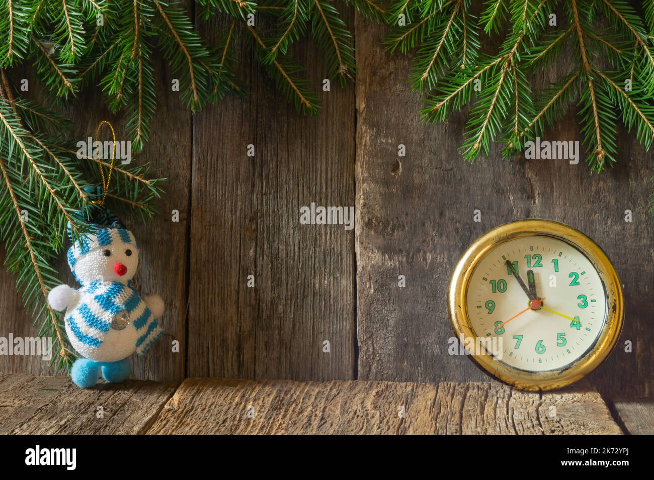 Neujahr Stillleben mit einer Uhr und einem Schneemann. Spielzeug auf dem Hintergrund eines alten Brettes Stockfoto