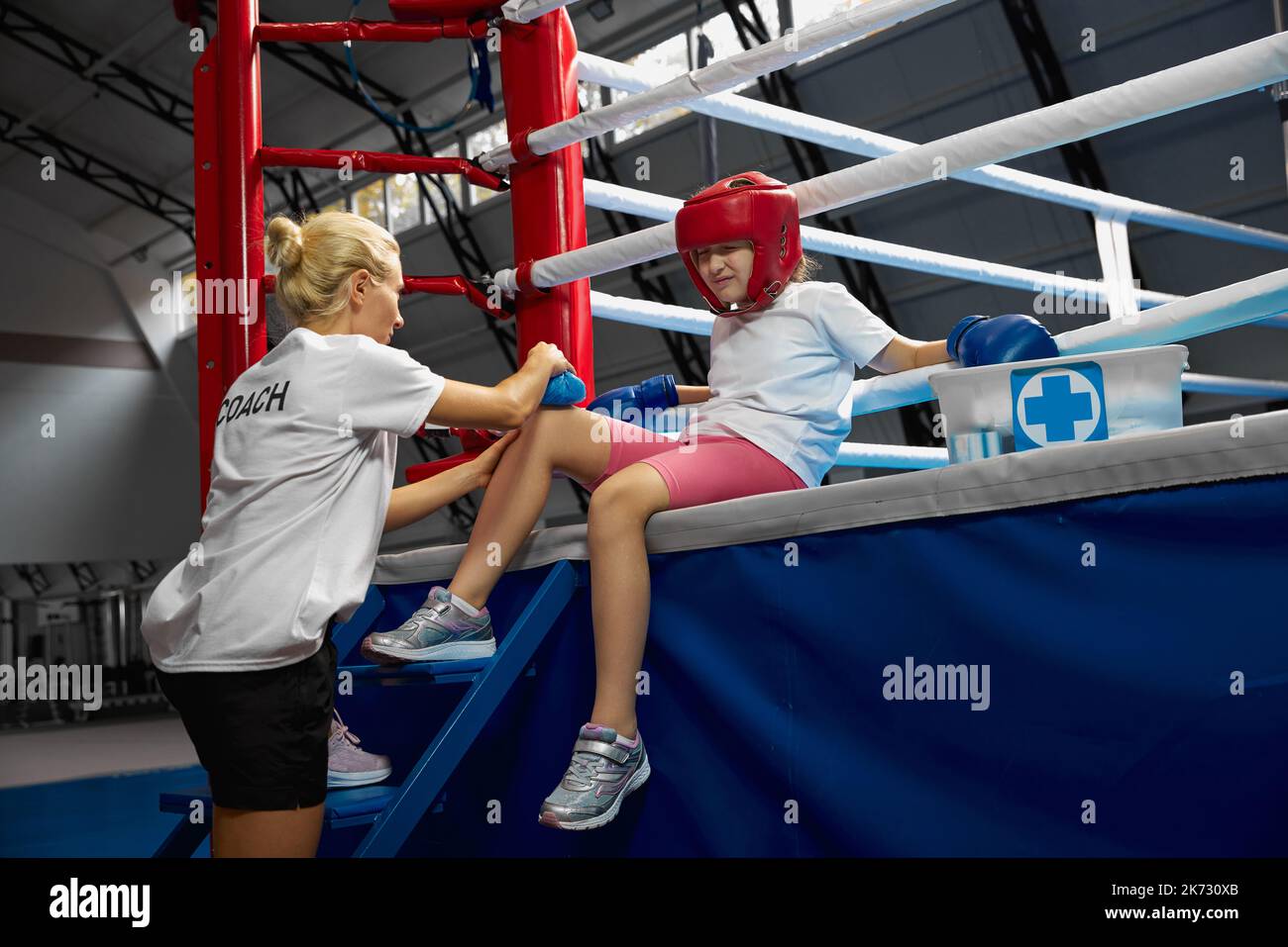 Persönlicher Trainer, Mannschaftstrainer leistet erste Hilfe für einen Athleten mit einer Knieverletzung. Boxtraining im Fitnessstudio. Sport, Medizin, Studium Stockfoto