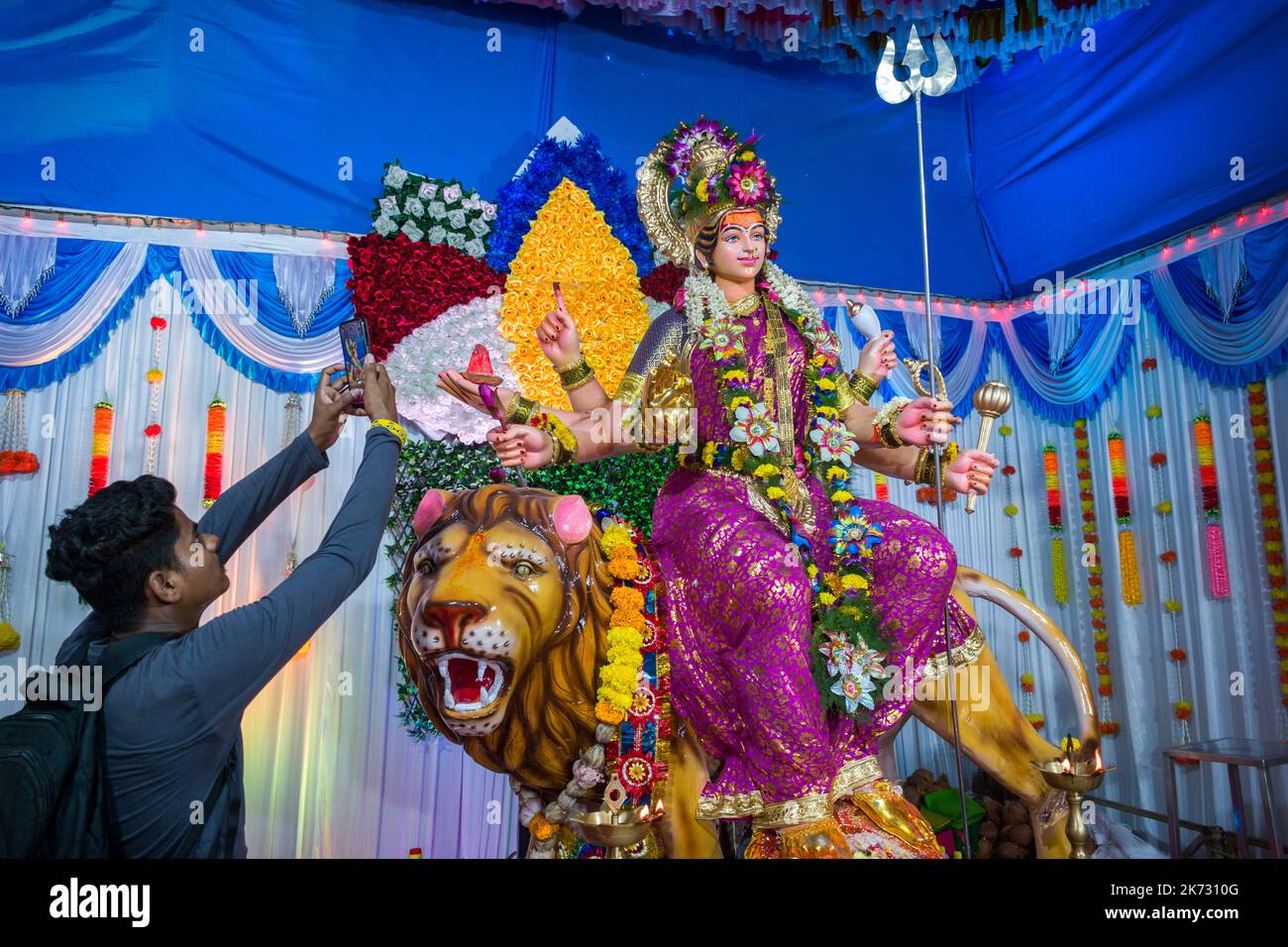 Ein Mann, der auf ein Bild eines Idols von Maa Durga in einem mandal in Mumbai für das verheißungsvolle indische Festival von Navratri klickt Stockfoto