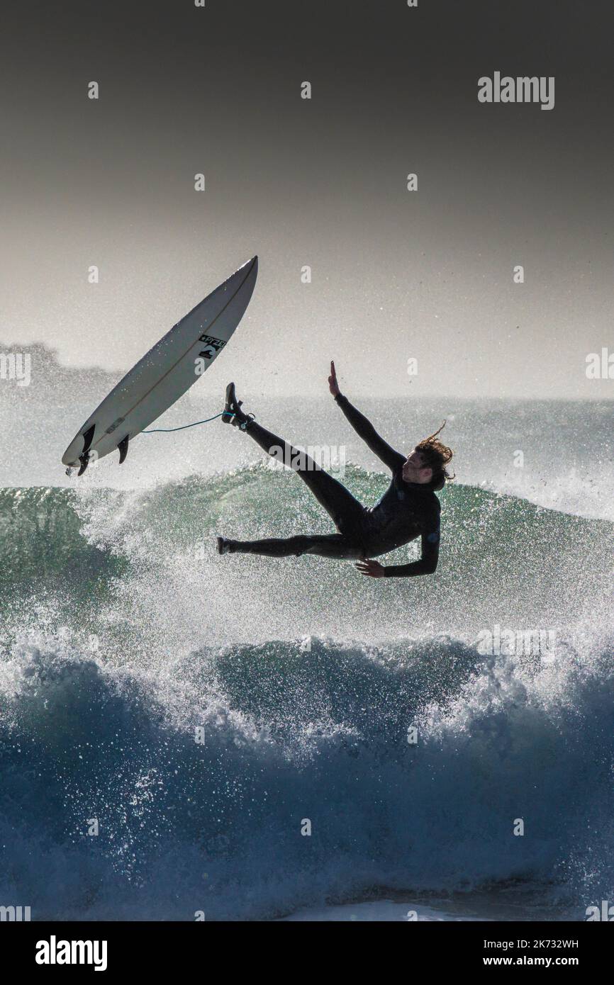Ein Surfer, der das Gleichgewicht verliert und bei Fistral in Newquay in Cornwall in Großbritannien auswischt. Stockfoto