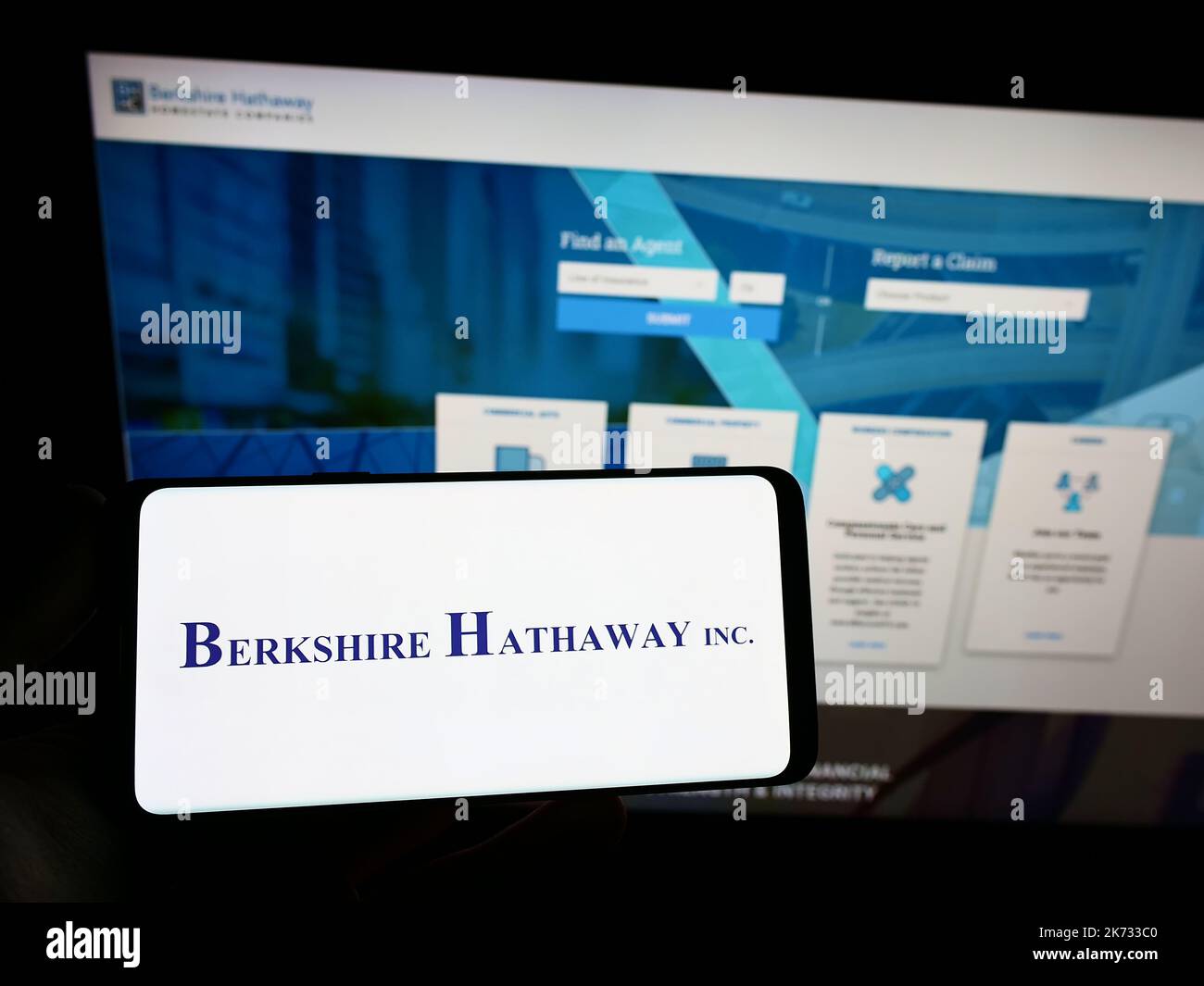 Person, die Smartphone mit dem Logo der US-Holding-Gesellschaft, der Firma, der Firma, auf dem Bildschirm vor der Website hält. Konzentrieren Sie sich auf die Telefonanzeige. Stockfoto