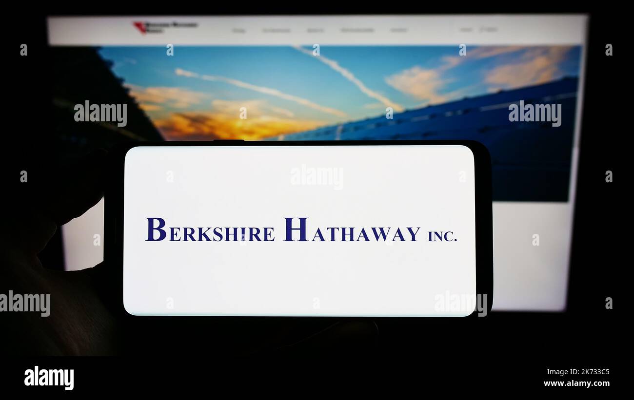 Person, die ein Mobiltelefon mit dem Logo der US-Holding-Gesellschaft, der Firma, der Firma, auf dem Bildschirm vor der Webseite, hält. Konzentrieren Sie sich auf die Telefonanzeige. Stockfoto