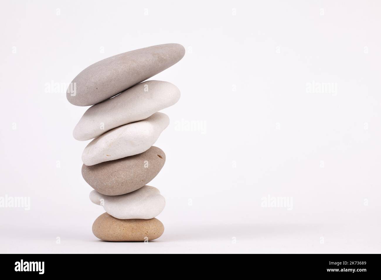 Umgekehrte Kieselstein-Zen-Säulen mit den kleinsten am Boden isoliert auf weißem Hintergrund Stockfoto