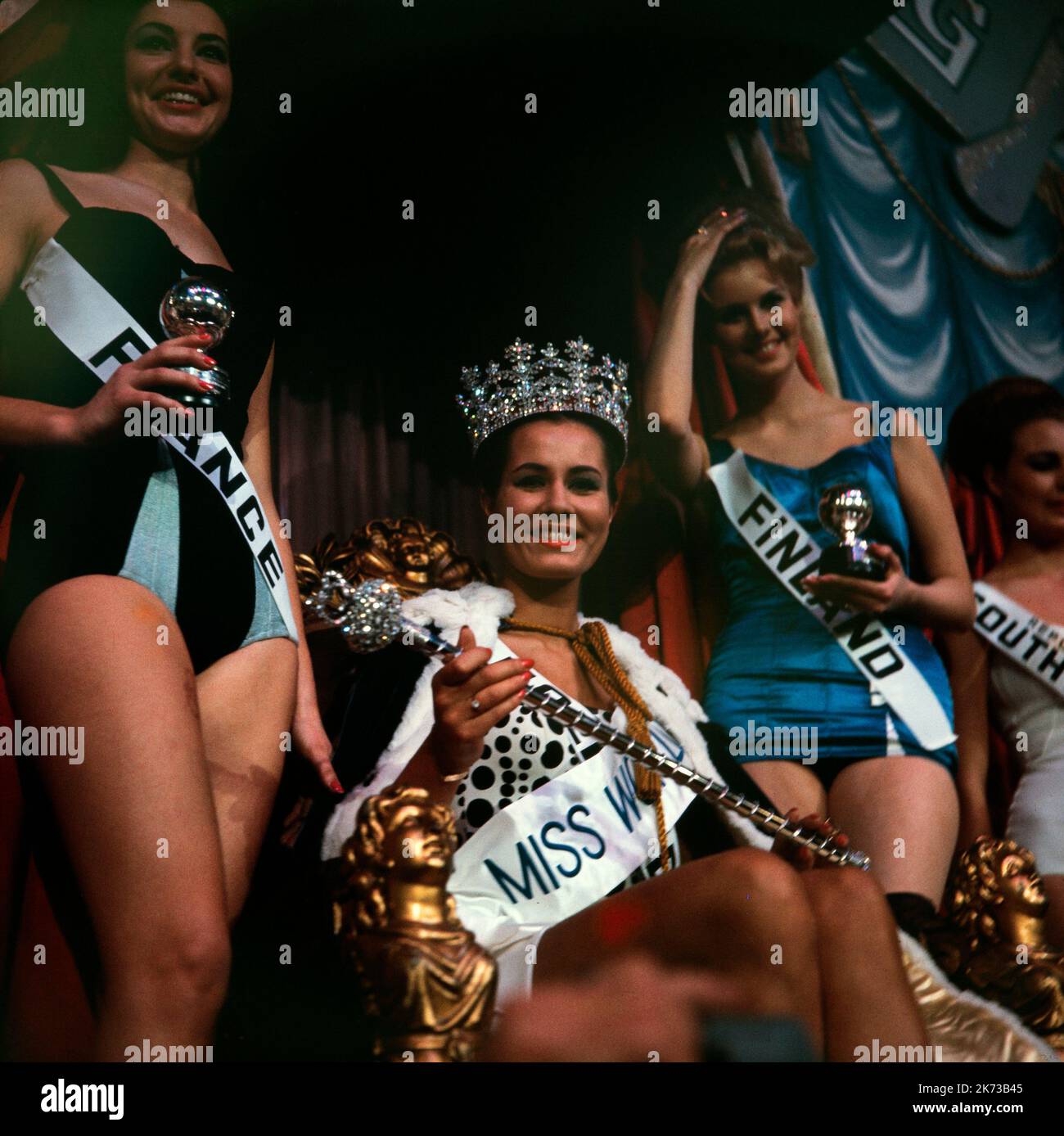 Die Gewinnerin des „Miss World“-Titels 1962, Catharina Lodders of the Netherlands, mit Miss France und Miss Finnland an ihrer Seite. Sie sitzt auf dem Thron und trägt eine Krone. Der Wettbewerb fand in London statt. Stockfoto