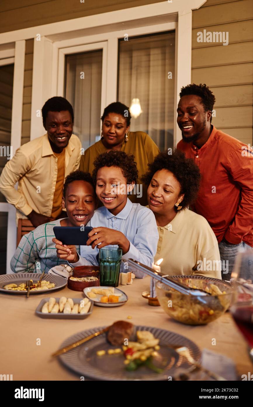Vertikales Porträt einer glücklichen afroamerikanischen Familie, die am Abend Selfie-Fotos auf der Terrasse des Hauses macht Stockfoto