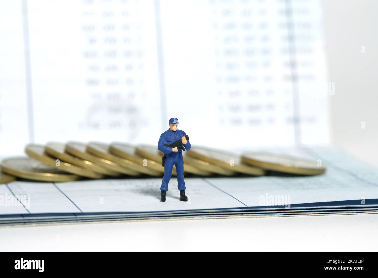 Miniatur Menschen Spielzeug Figur Fotografie. Konzept zum Schutz von Bankkonten. Ein Sicherheitsbeamter, der über dem Bankkonto mit einer goldenen Geldmünze steht. Isola Stockfoto