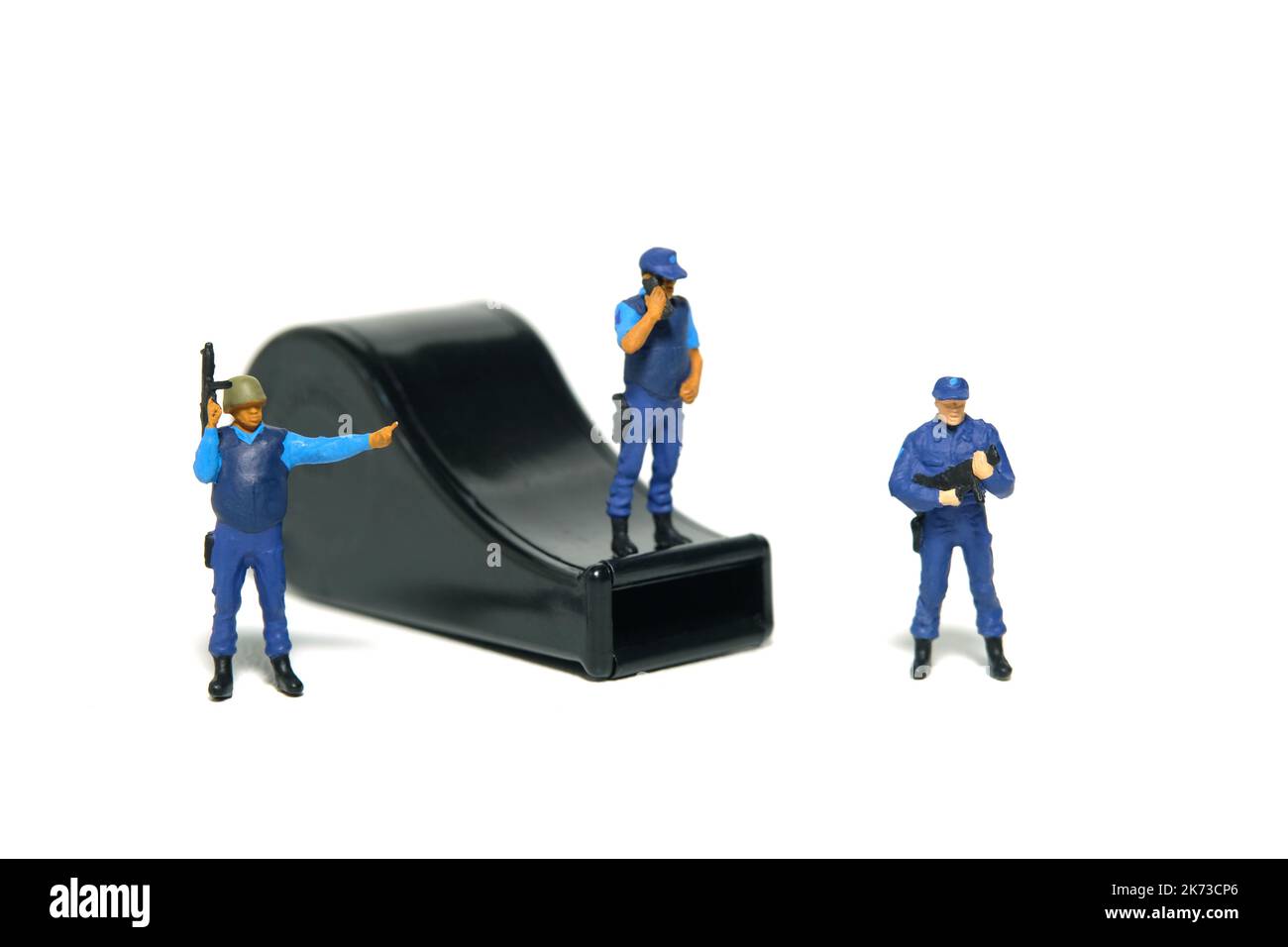 Miniatur Menschen Spielzeug Figur Fotografie. Konzept für den Schutz von JustizmitarbeiterInnen und WhistleblowerInnen. Ein Sicherheitsbeamter, der über einer schwarzen Pfeife steht. Stockfoto