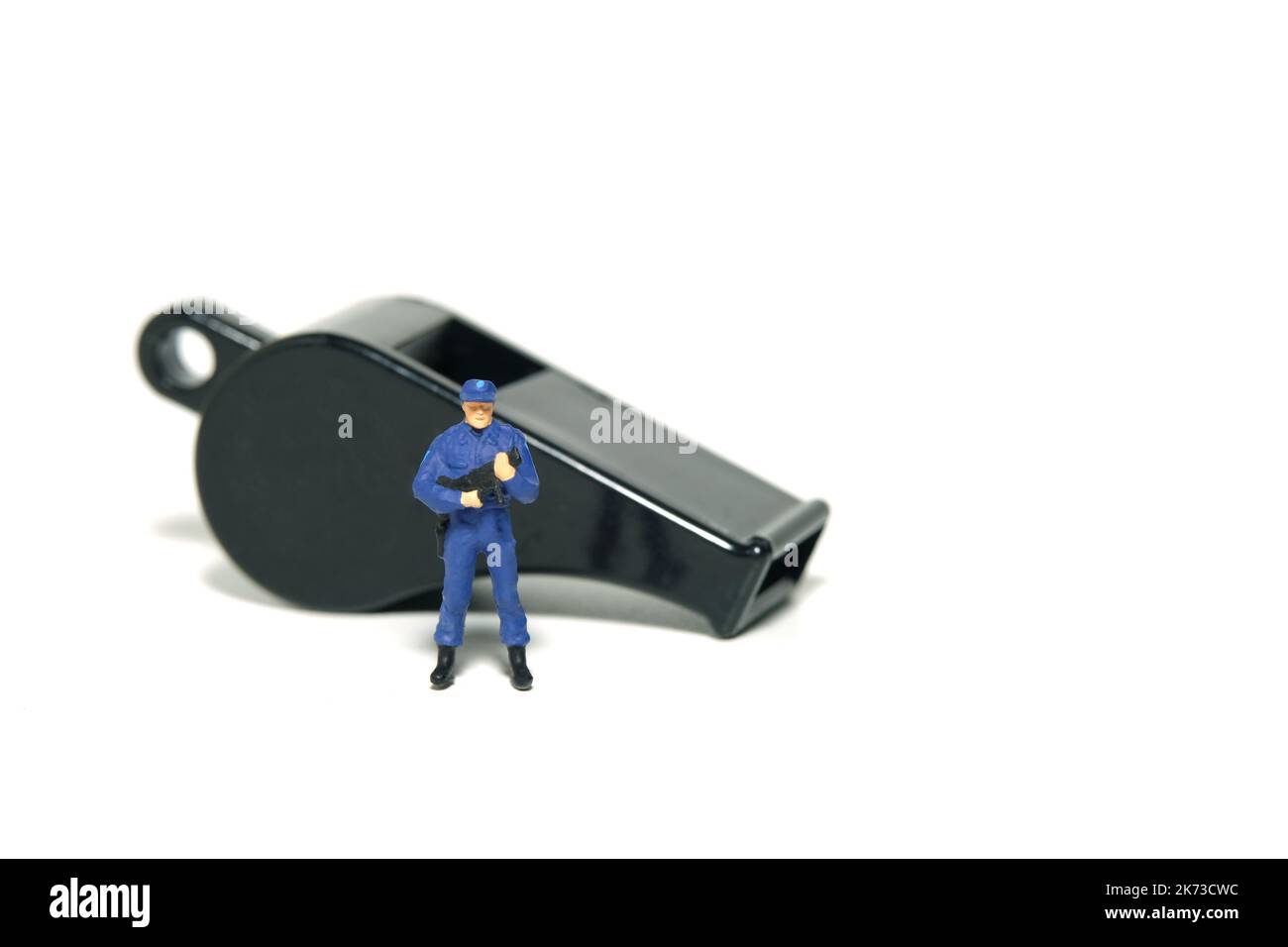 Miniatur Menschen Spielzeug Figur Fotografie. Konzept für den Schutz von JustizmitarbeiterInnen und WhistleblowerInnen. Ein Sicherheitsbeamter, der vor einem schwarzen Whis steht Stockfoto