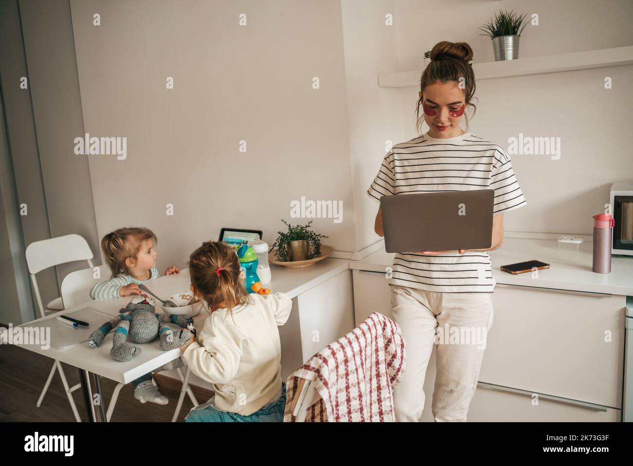 Beschäftigte Freiberuflerin und ihre Kinder in der Küche Stockfoto