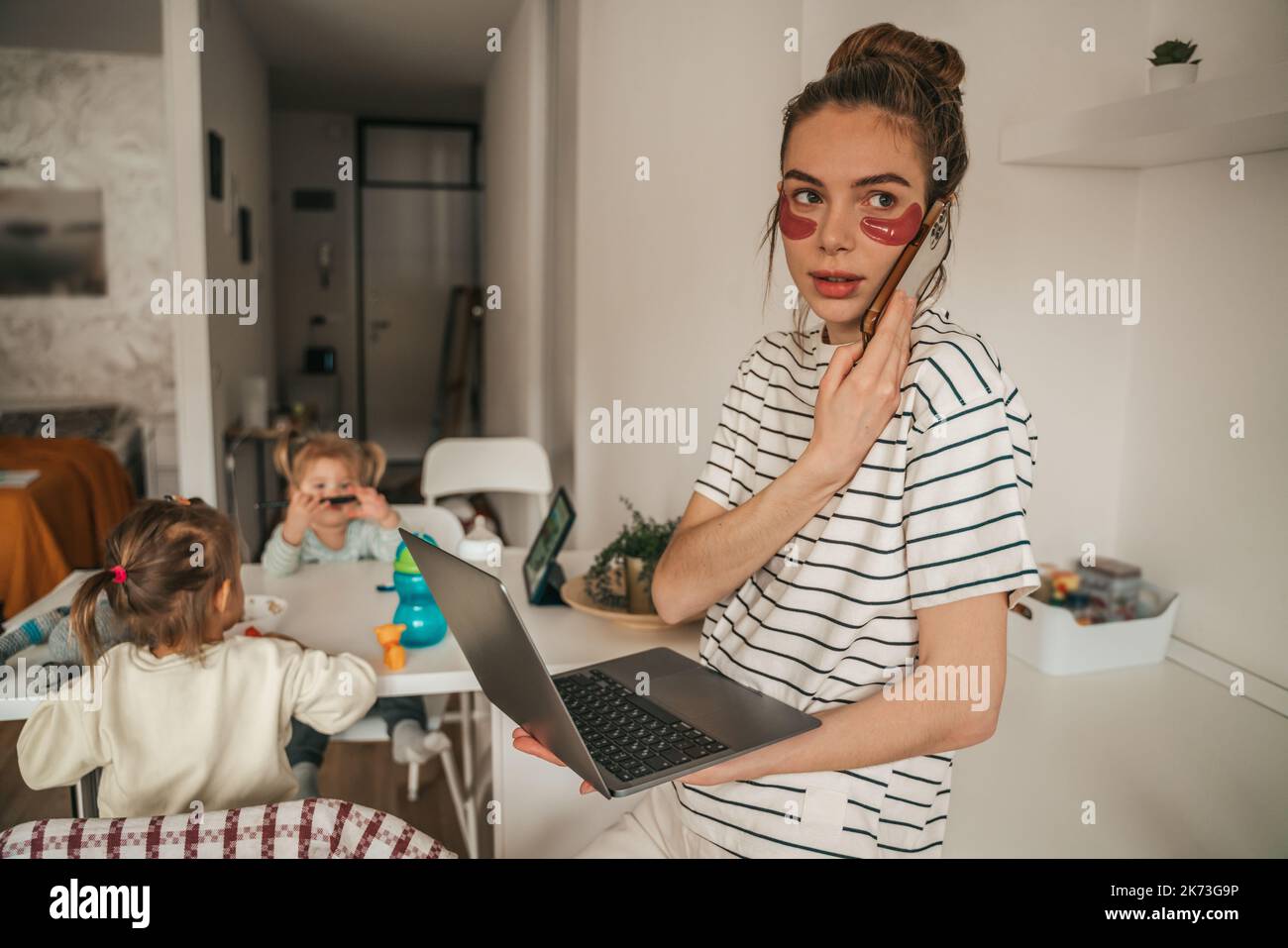 Beschäftigt freiberufliche Mutter und Kinder spielen in der Küche Stockfoto