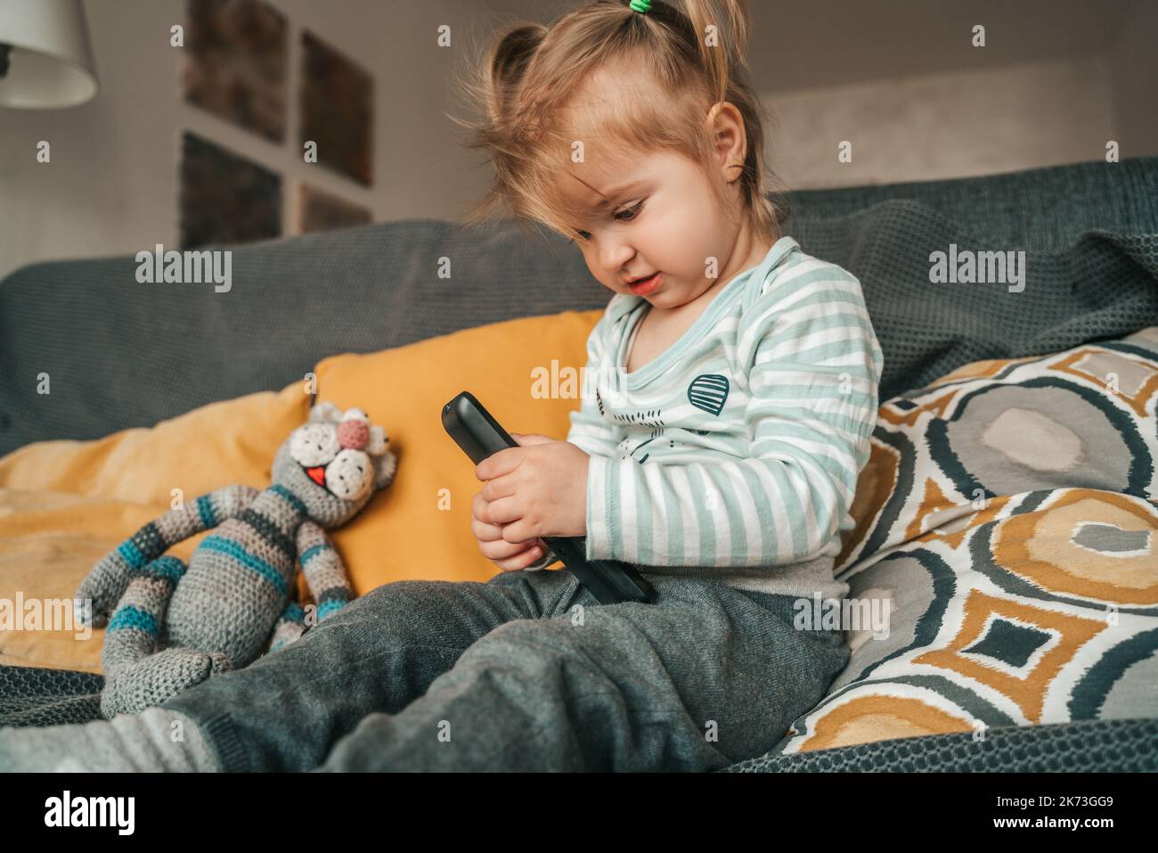 Ruhiges weibliches Kind, das mit dem TV-Zubehör spielt Stockfoto