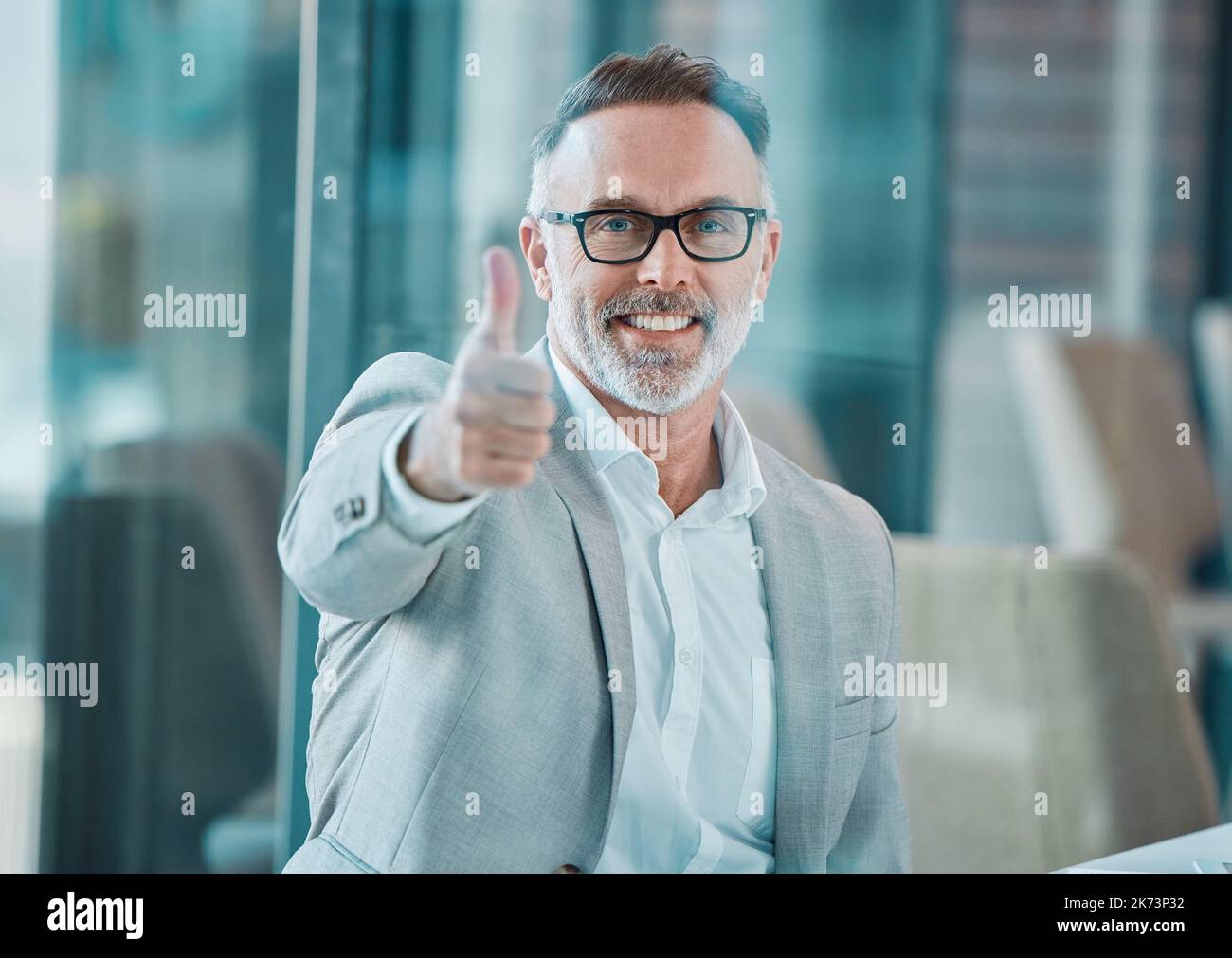 Verbreiten Sie Liebe überall Sie gehen. Ein reifer Geschäftsmann, der bei der Arbeit Daumen nach oben zeigt. Stockfoto