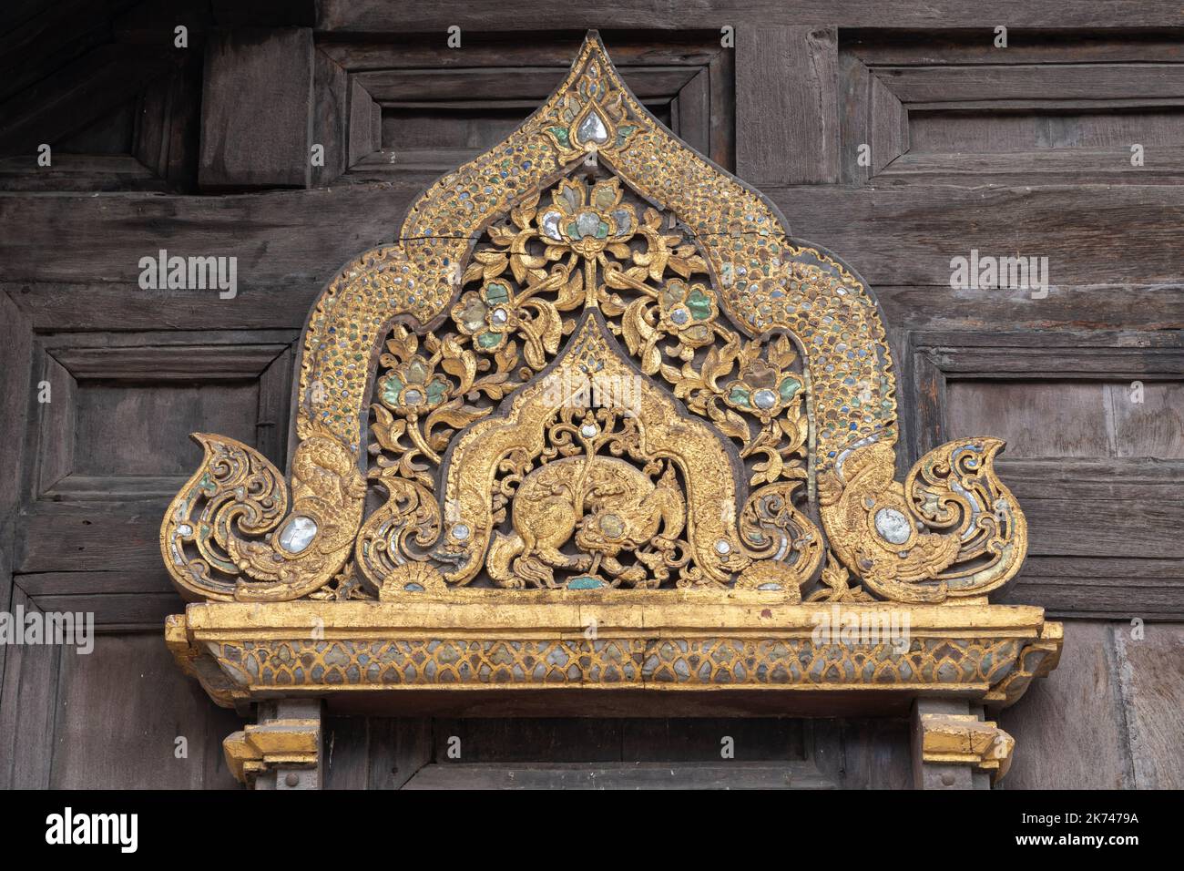 Nahaufnahme der wunderschönen alten vergoldeten Holzschnitzerei über dem Fenster des historischen Wahrzeichens Wat Phan Tao buddhist Temple Fassade, Chiang Mai, Thailand Stockfoto