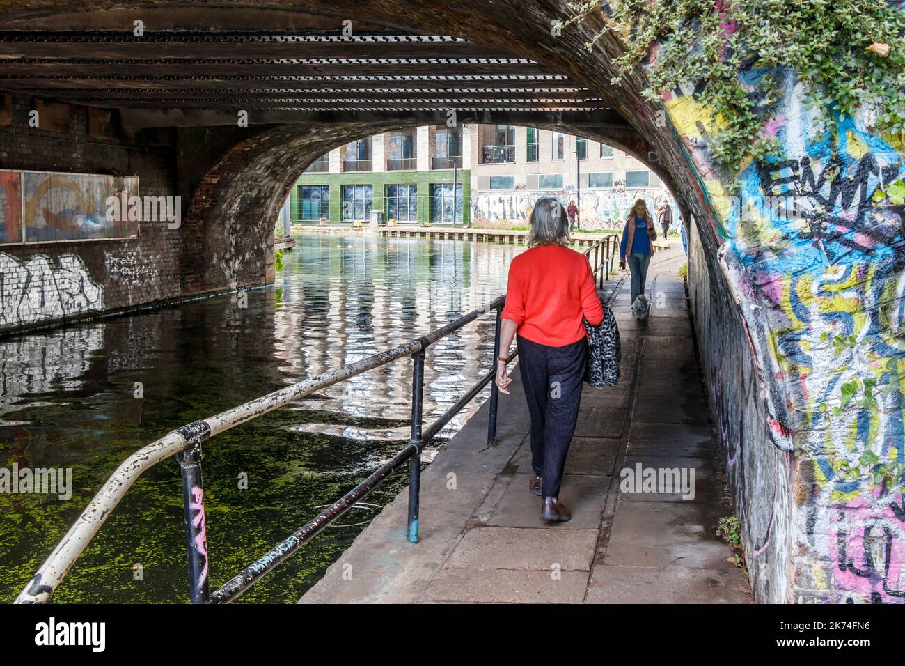 Eine Frau geht entlang des Regent Canal Towpath unter der Camden Street Bridge, London, Großbritannien Stockfoto