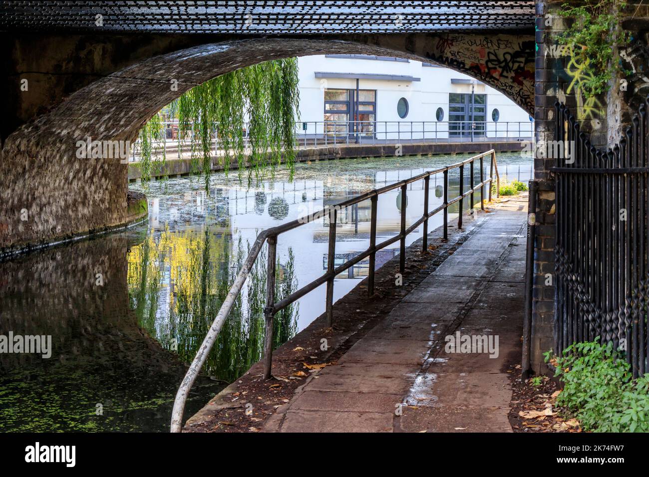 Eine Frau geht entlang des Regent Canal Towpath unter der Camden Road Bridge, London, Großbritannien Stockfoto
