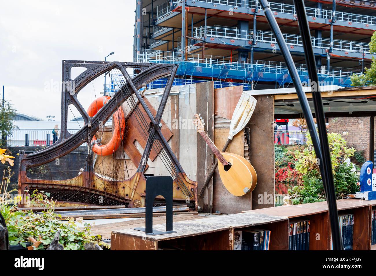 Musikinstrumente, ein Klavierrahmen und andere Bric-a-brac auf Word on the Water, einer schwimmenden Buchhandlung am Regents Canal am King's Cross, London, Großbritannien Stockfoto