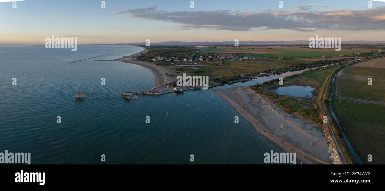 Luftaufnahme der Fischerhütten am Ufer der Mündung bei Sonnenuntergang, italienische Fischmaschine, genannt ''trabucco'', Lido di Dante, Ravenna in der Nähe des Comacchio-Tals. Stockfoto