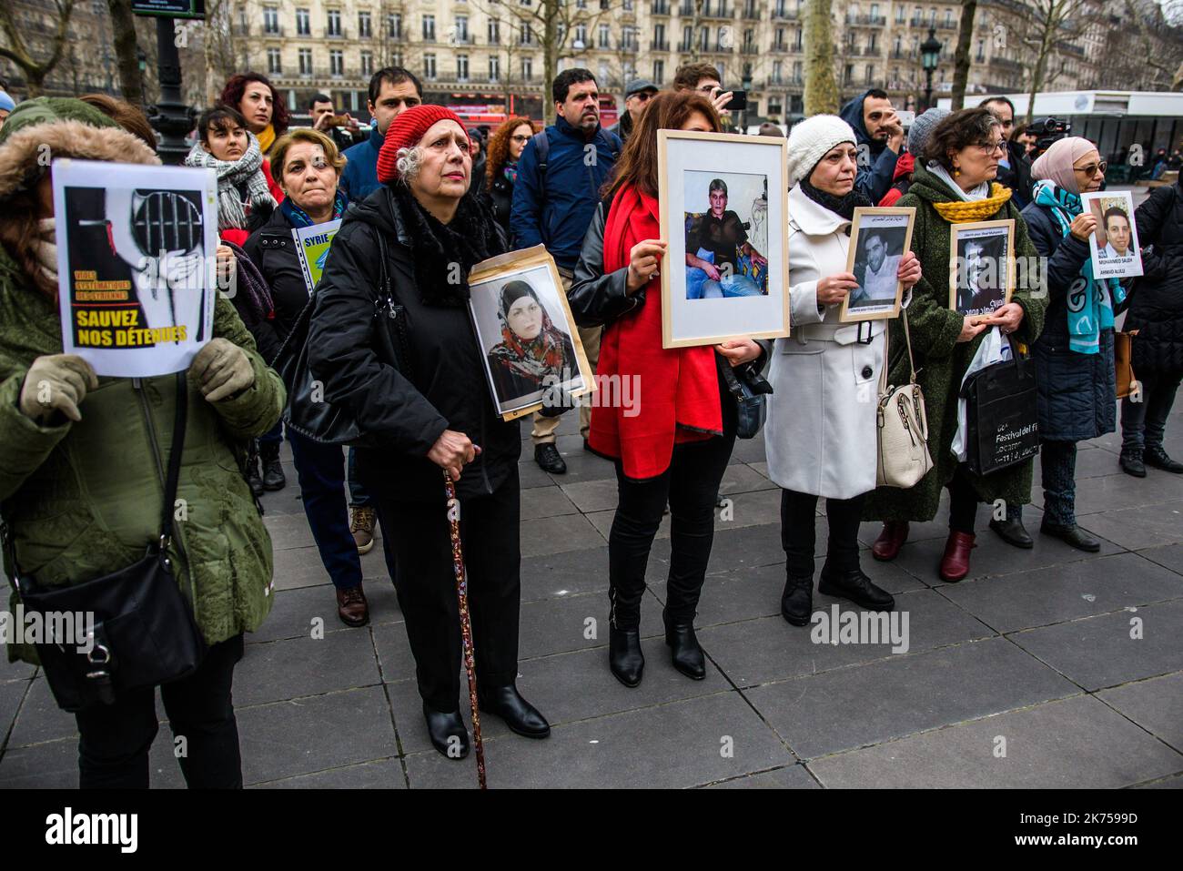 Frauen halten Fotos von verschwundenen und inhaftierten Syrern hoch, während sie neben einem Londoner Doppeldeckerbus stehen, während sie am 27. Januar 2018 auf dem Republique-Platz in Paris, Frankreich, eine von „Familien für die Freiheit“ organisierte Demonstration veranstalteten Stockfoto