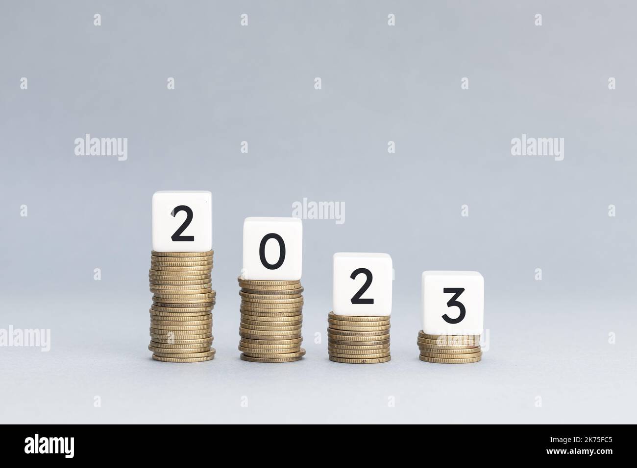 2023 Jahre Konzept der Finanzkrise. Münzhaufen, der eine absteigende Grafik bildet, mit Block oben mit Text 2023. Speicherplatz kopieren Stockfoto