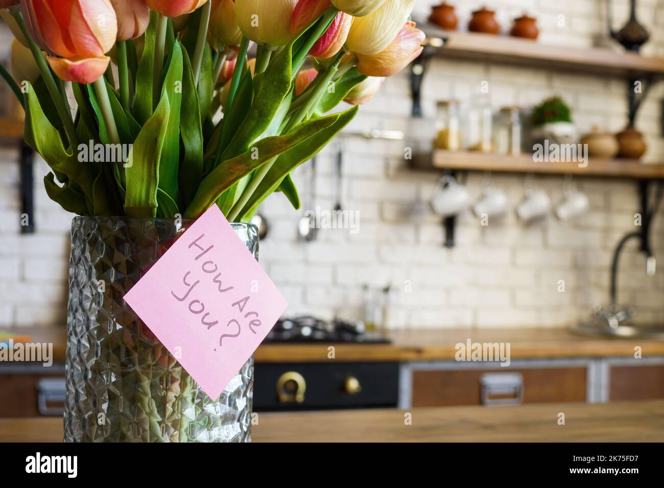 Vase mit Blumen zu Hause und Aufkleber mit wie sind Sie Frage. Stockfoto