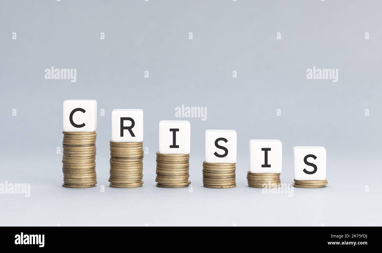Konzept der Wirtschaftskrise. Stapel von Münzen bilden eine absteigende Grafik mit Blöcken auf der Oberseite mit Text Krise. Speicherplatz kopieren Stockfoto