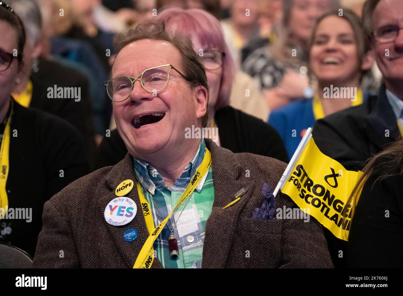 SNP-Konferenz 2022 in Aberdeen. Ein Delegierter, der eine SNP-Flagge trägt, lacht, wenn er der Rede zuhört. Stockfoto