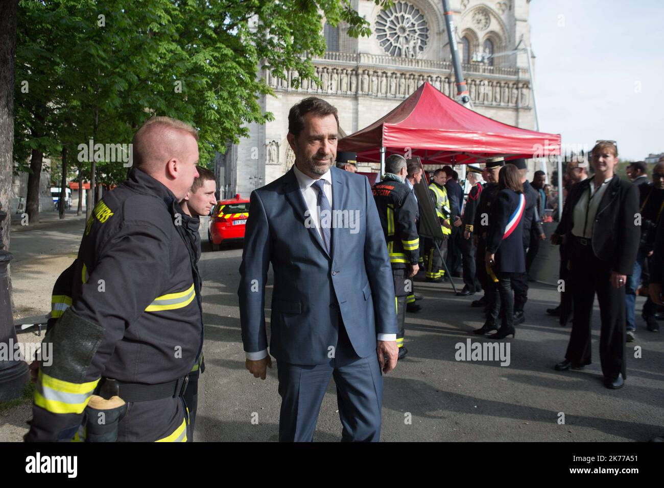 Der französische Innenminister Christophe Castaner (3L) schüttelt einem Feuerwehrmann die Hände, als er am 18. April 2019 in Paris die Kathedrale Notre Dame besichtigt. Frankreich würdigte am 18. April 2019 die Pariser Feuerwehrleute, die die Kathedrale Notre-Dame vor dem Zusammenbruch retteten, tagelang, während Bauarbeiter eilig einen Bereich über einem der berühmten rosarosenförmigen Fenster der Kirche und anderen gefährdeten Bereichen des feuerbeschädigten Denkmales sicherten Stockfoto