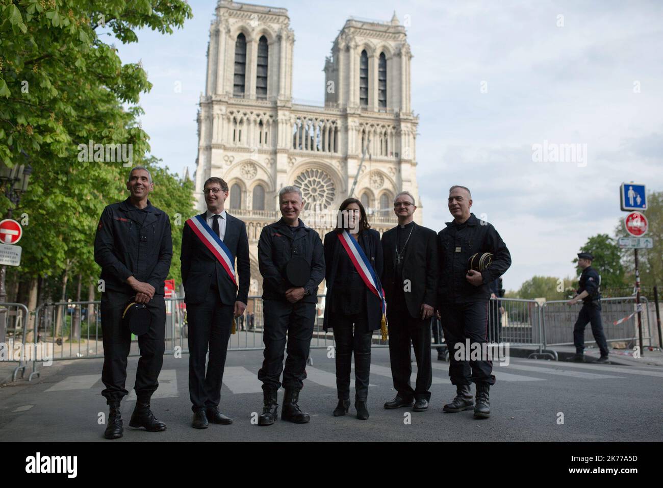 Anne Hidalgo und Firefighters posiert für ein Bild vor der Kathedrale Notre Dame am 18. April 2019 in Paris. Frankreich würdigte am 18. April 2019 die Pariser Feuerwehrleute, die die Kathedrale Notre-Dame vor dem Zusammenbruch retteten, tagelang, während Bauarbeiter eilig einen Bereich über einem der berühmten rosarosenförmigen Fenster der Kirche und anderen gefährdeten Bereichen des feuerbeschädigten Denkmales sicherten Stockfoto