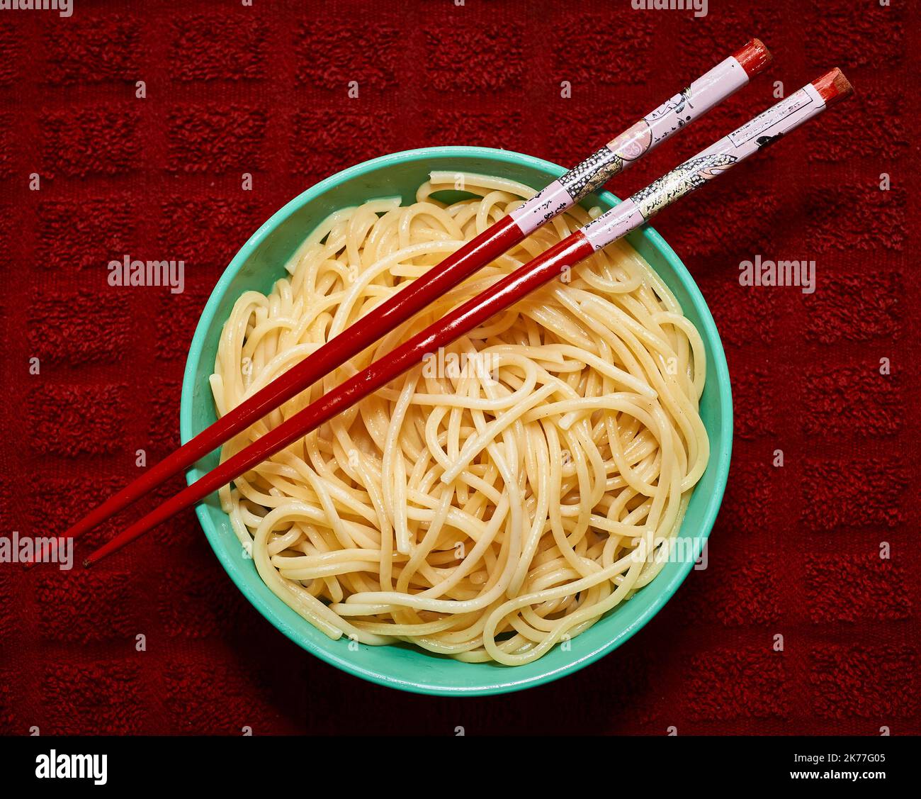 Bio-Grieß-Pasta wird in einer kleinen Schale mit rotem Chapstick über einem roten Küchetücher serviert Stockfoto