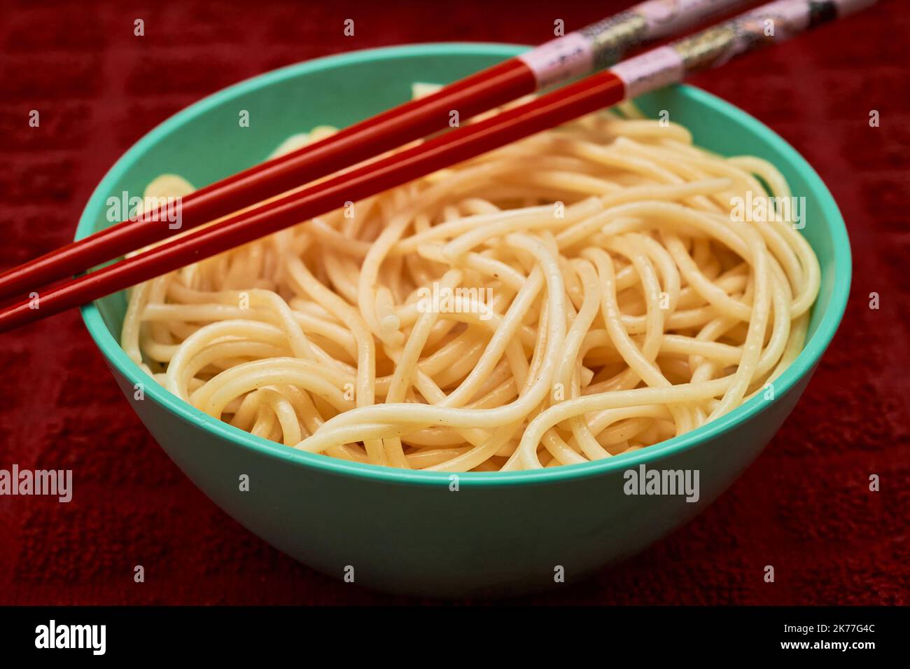 Bio-Grieß-Pasta wird in einer kleinen Schale mit rotem Chapstick über einem roten Küchetücher serviert Stockfoto