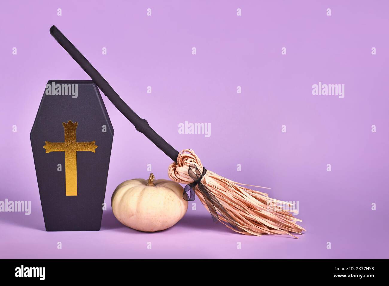 Halloween-Arrangement mit Sarg-Geschenkbox, Baby-Buh-Kürbissen und Hexenbesen auf purpurem Hintergrund mit Kopierraum Stockfoto