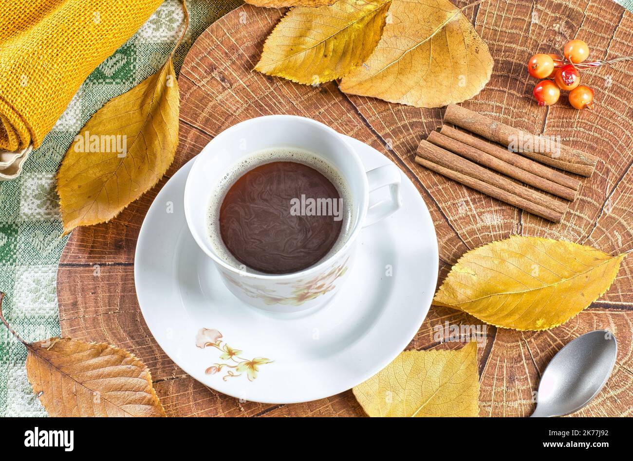 Warmer Kaffee in einer Tasse auf einem mit Herbstblättern und Holz verzierten Tisch Stockfoto