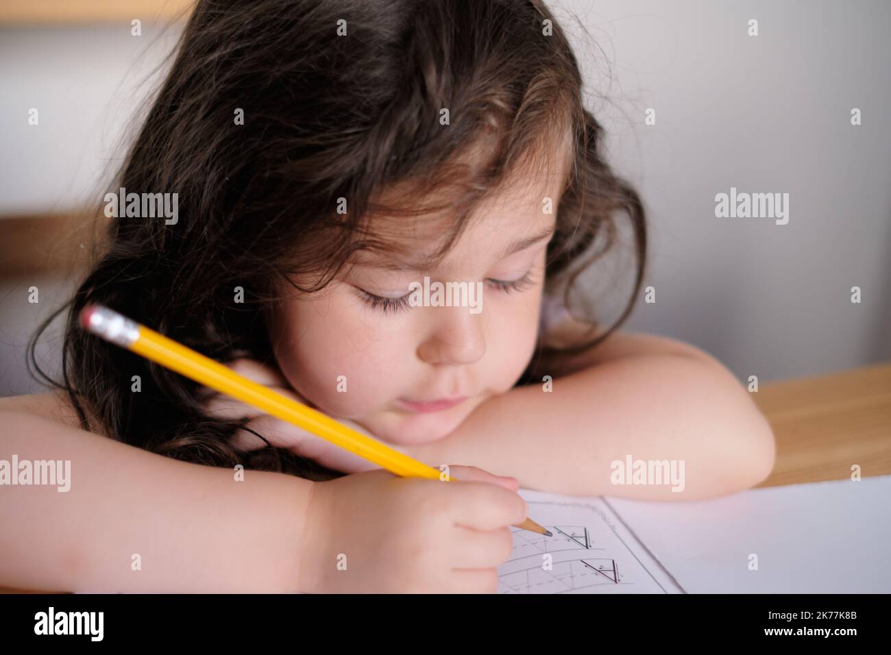 Young Pretty ist ein Mädchen, das Buchstaben in einem Buch verfolgt Stockfoto