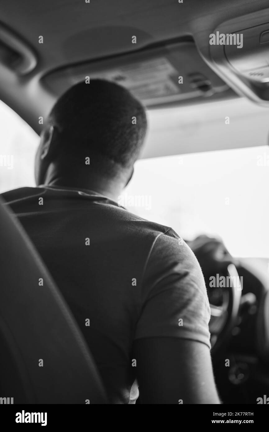 Eine vertikale monochrome Aufnahme eines Mannes, der ein Auto fährt Stockfoto