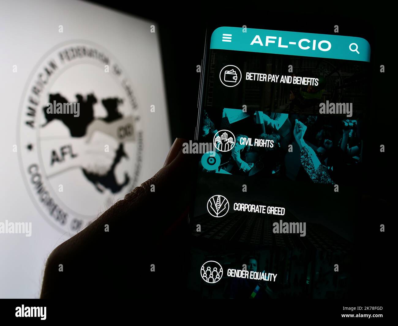 Person, die Mobiltelefon mit der Webseite des amerikanischen Gewerkschaftsbundes AFL-CIO auf dem Bildschirm vor dem Logo hält. Konzentrieren Sie sich auf die Mitte des Telefondisplays. Stockfoto