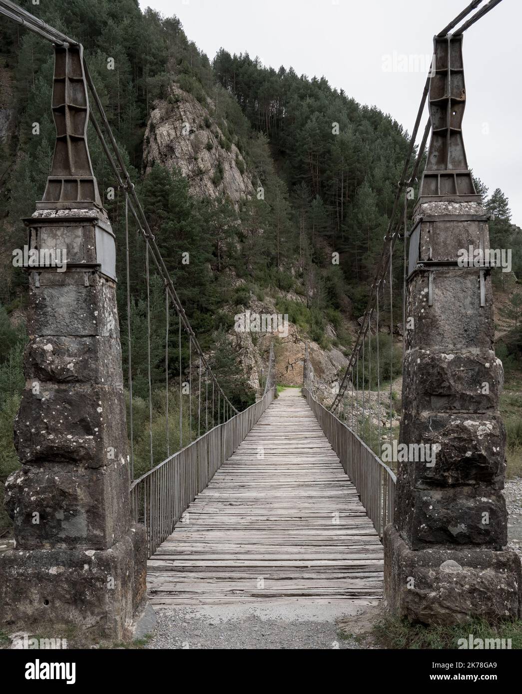 Ein steinerner Pier, eine Hängebrücke mit Kabelaufhängung über einen Bergfluss Stockfoto
