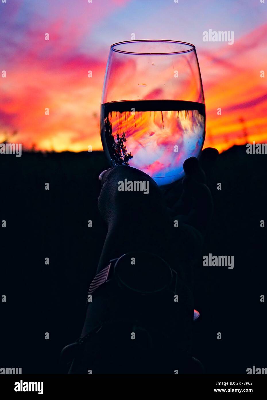 Ein Glas Weißwein mit einem farbenfrohen Sonnenuntergang Stockfoto