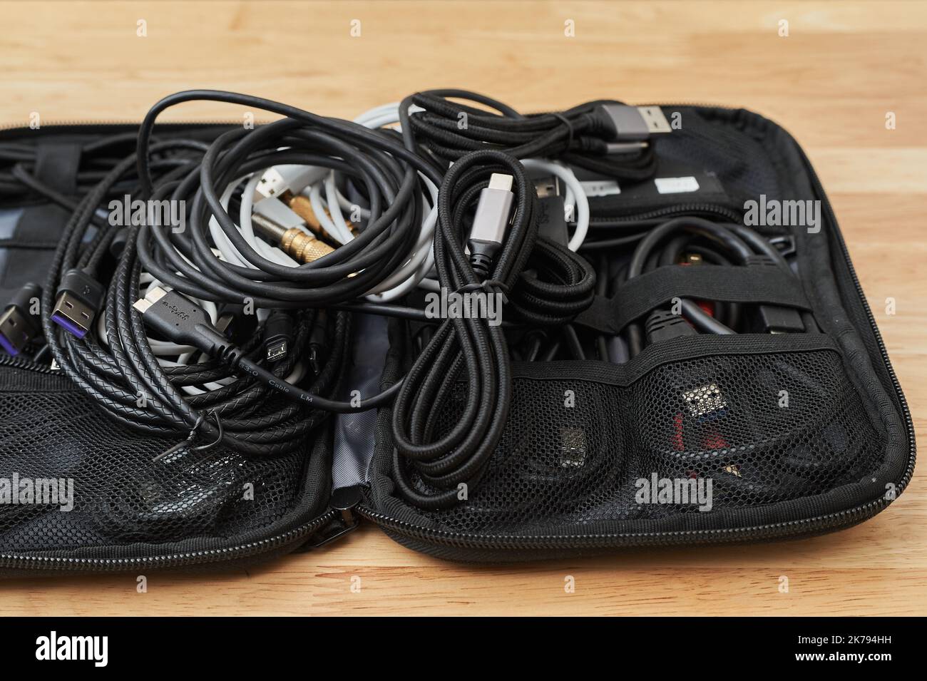 Elektro- und Ladekabel verschiedener Art, die in einem Reisekoffer auf einem Arbeitstisch liegen Stockfoto