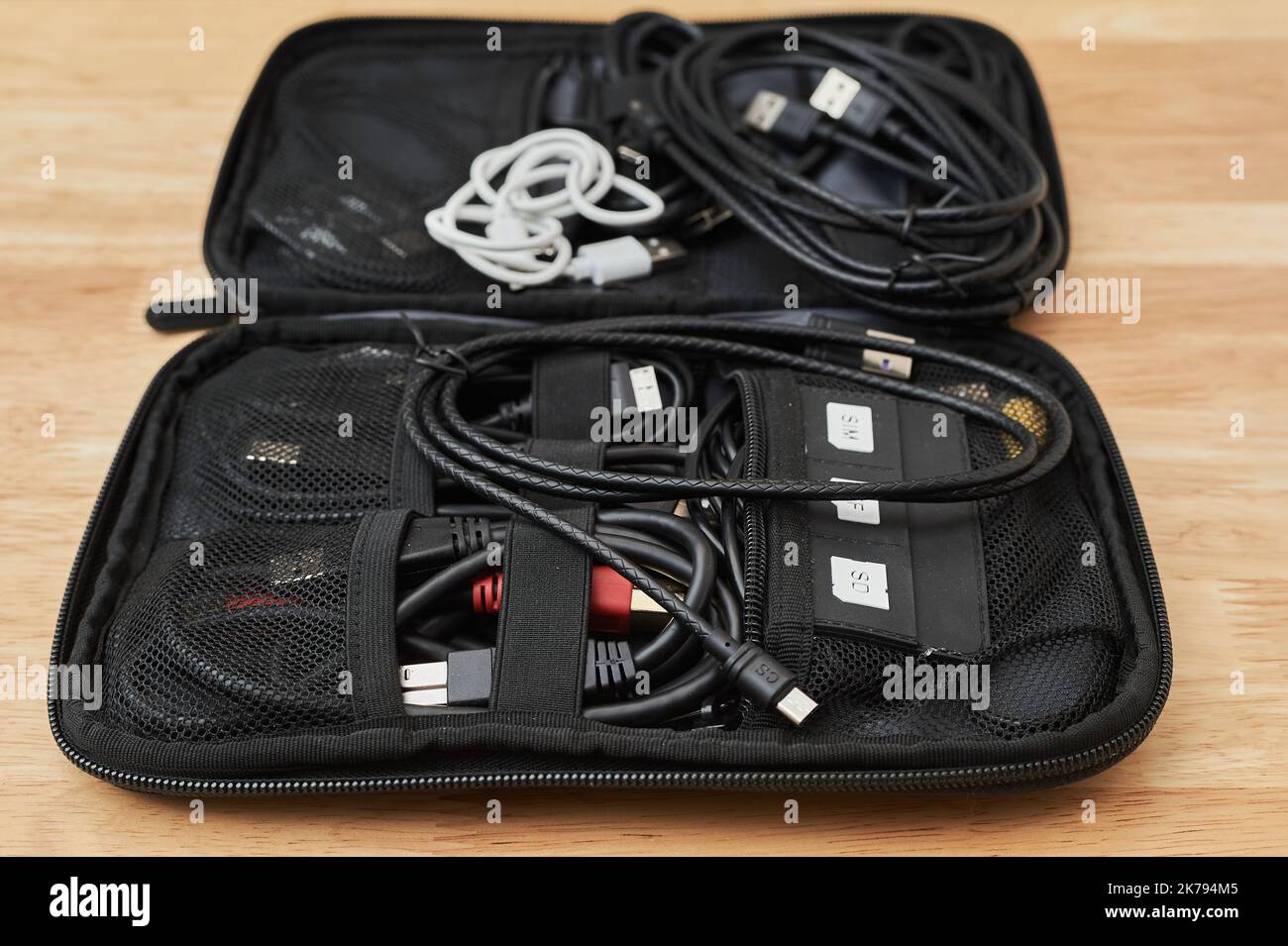 Elektro- und Ladekabel verschiedener Art, die in einem Reisekoffer auf einem Arbeitstisch liegen Stockfoto