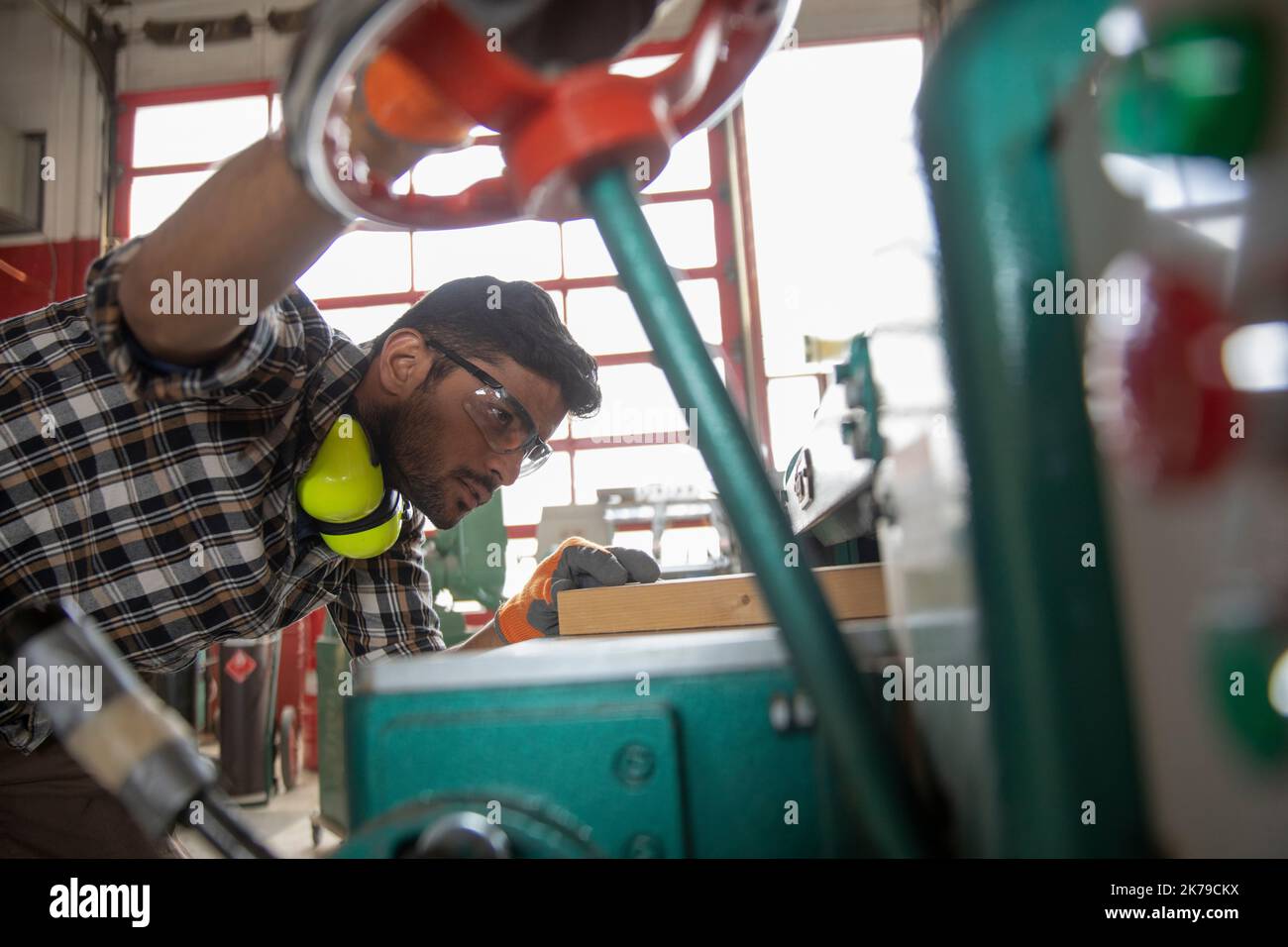 Junger Mann, der Holz im Makerraum sägt Stockfoto