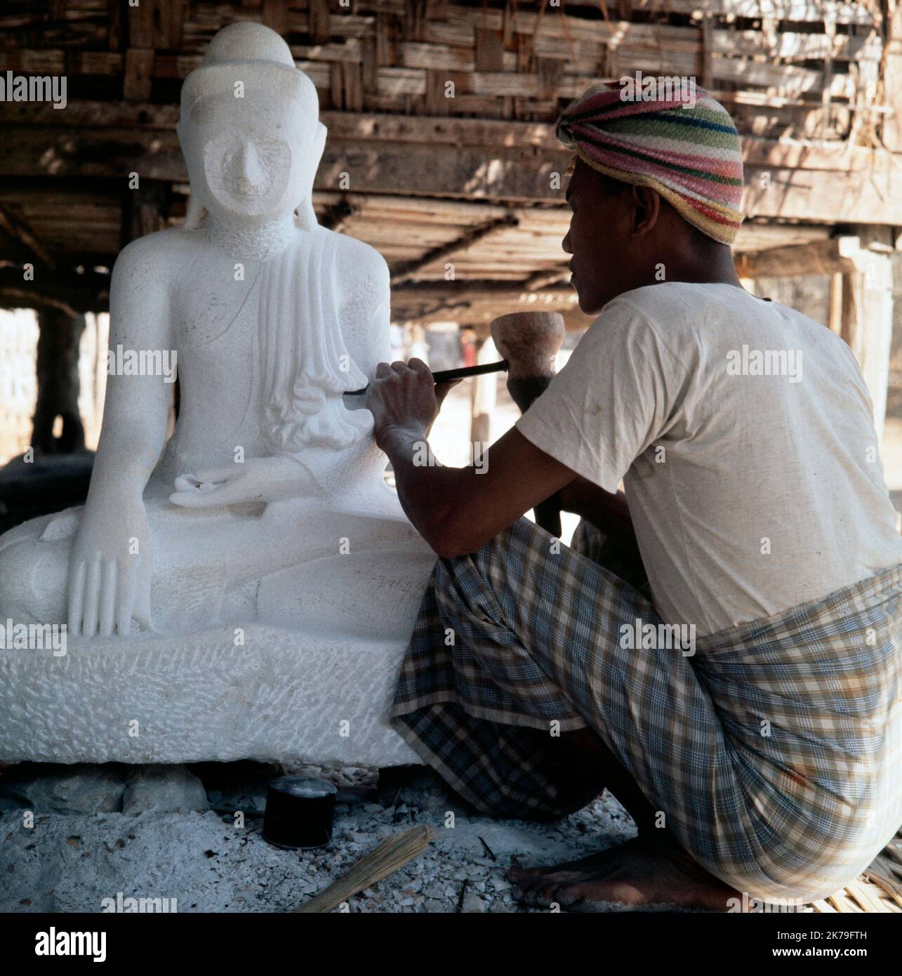 Ein Vintage-Farbfoto aus dem Jahr 1960s, das eine traditionelle Skulptur oder einen Schnitzer zeigt, die an einer Buddha-Statue in Burma arbeitet. Stockfoto