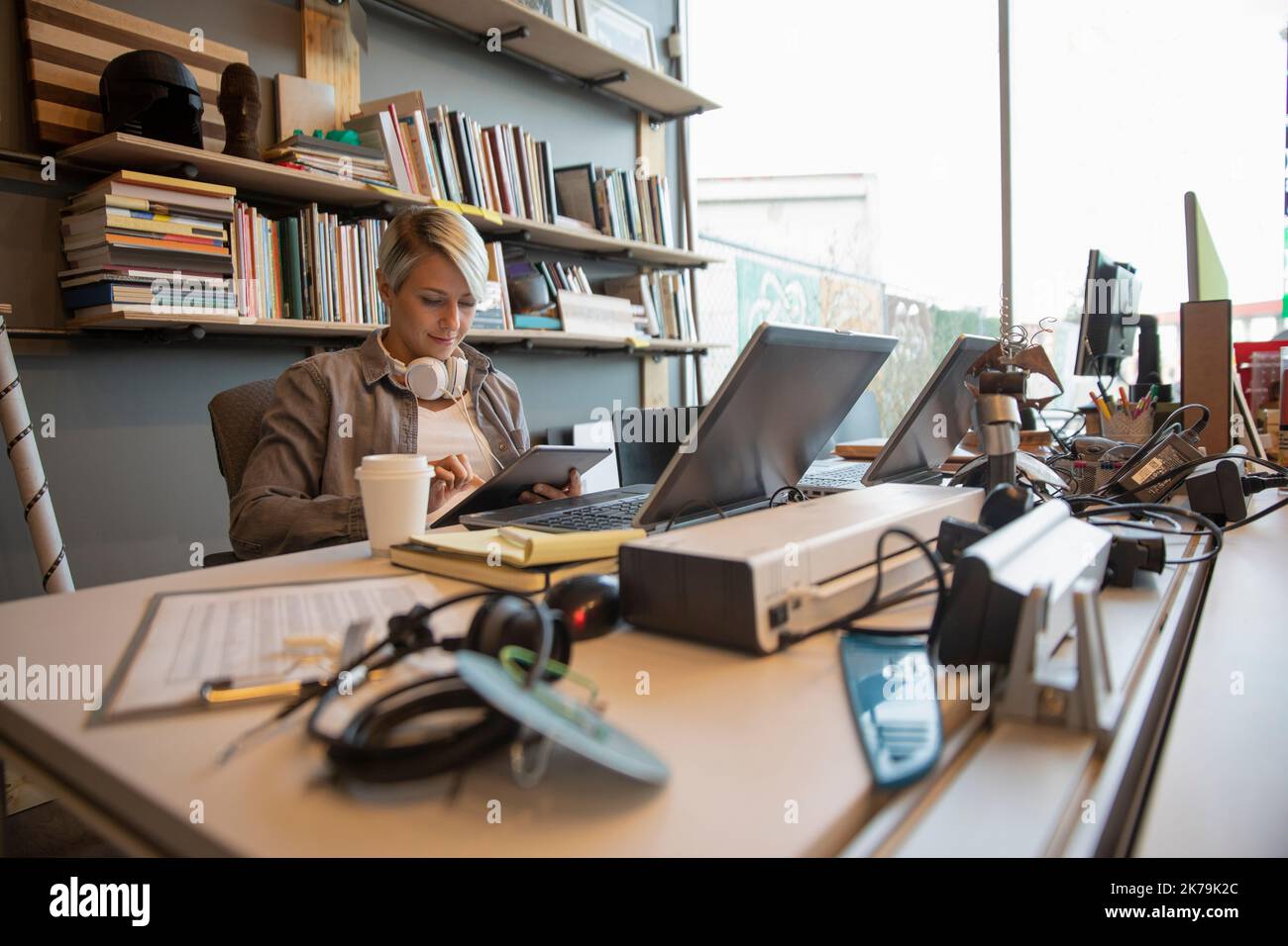 Junge Frau sitzt am Schreibtisch mit Tablet in einem kreativen Büro Stockfoto