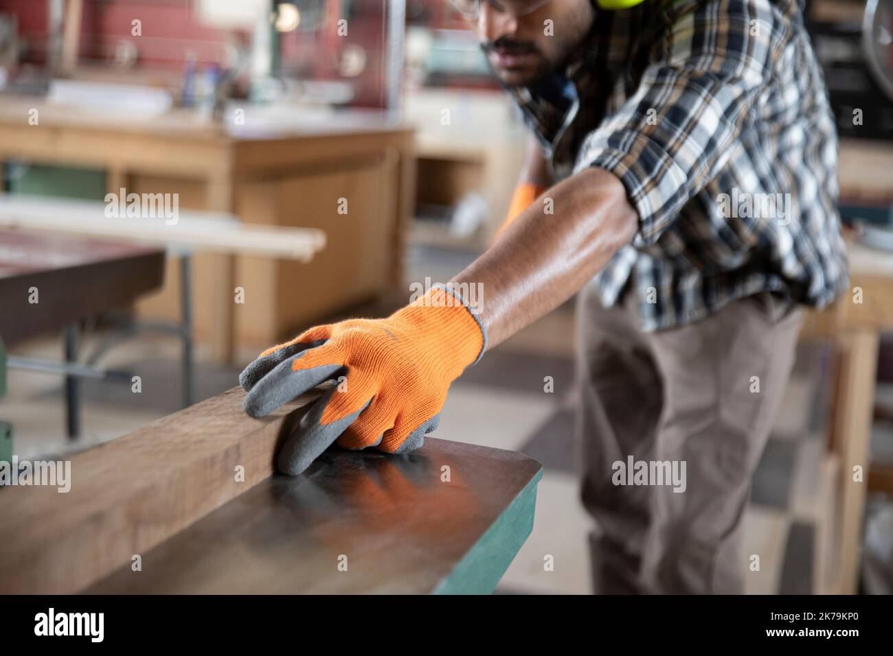 Mann mit Schutzhandschuhen, der Holz im Makerbereich hält Stockfoto
