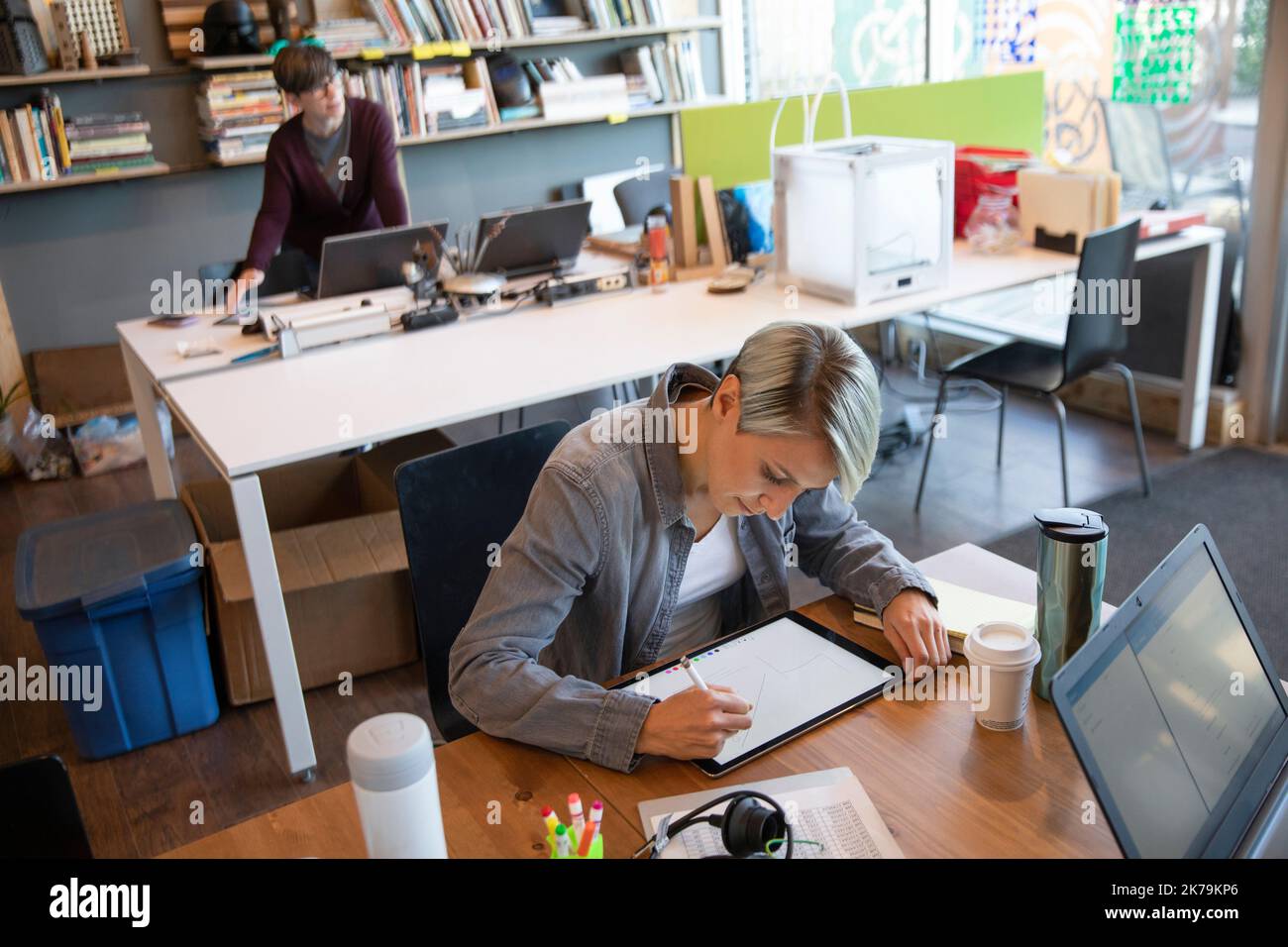 Junge Frau, die im kreativen Büro auf einem Stifttablett malt Stockfoto
