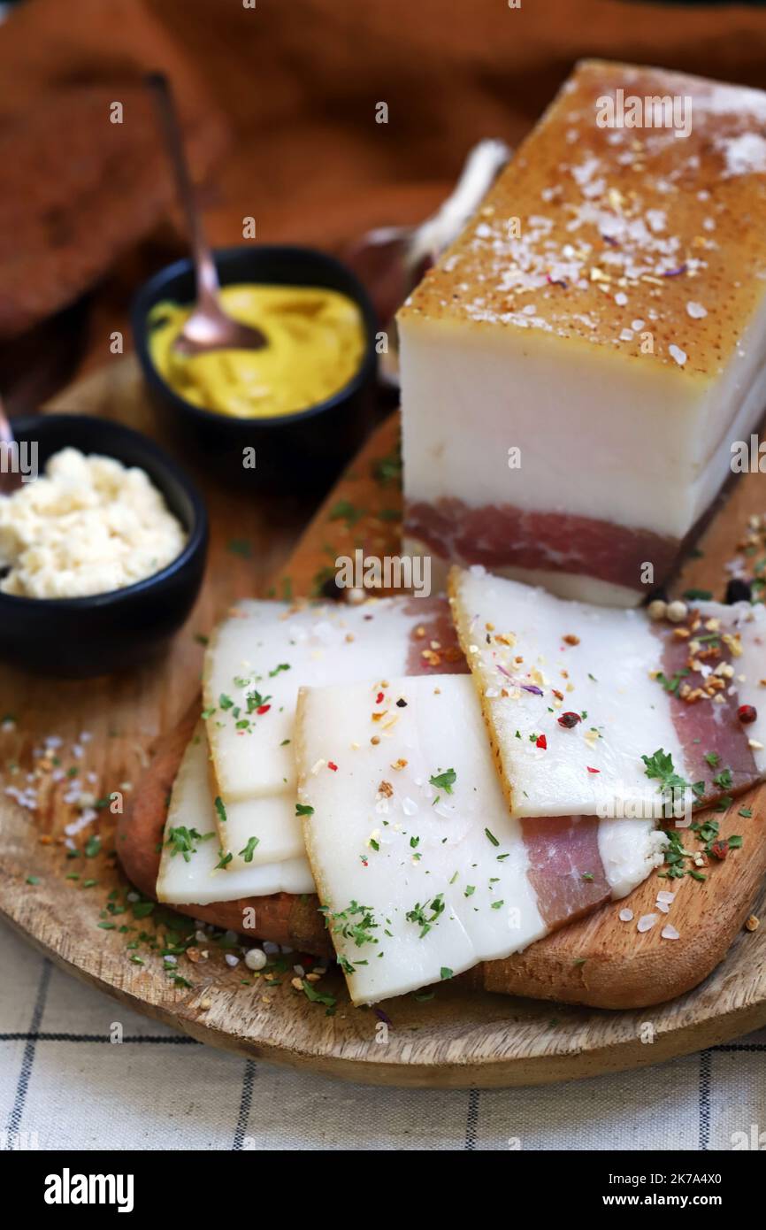 Frischer Schmalz mit Fleischschicht auf einem Holzbrett mit Gewürzen, Senf und Meerrettich. Leckerer Snack. Speck. Stockfoto