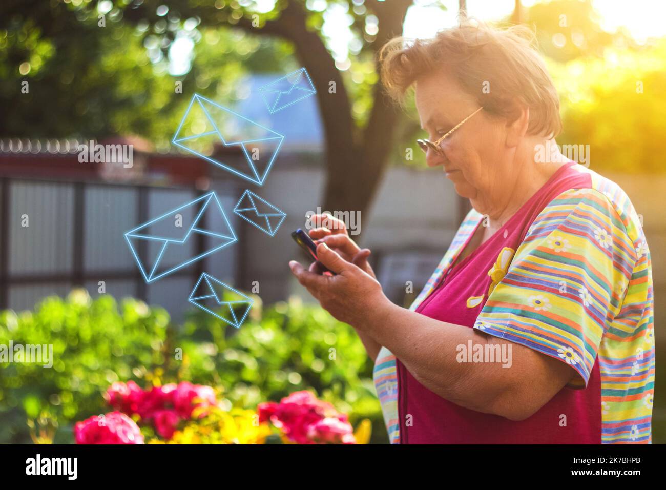 Eine 65-jährige Frau schaut auf das Telefon im Hof Oma lernt, wie man das Telefon verwendet Porträt einer gut aussehenden reifen Frau mit Smart Stockfoto