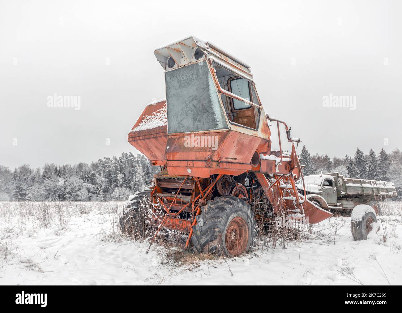 Rot gebrochene gefrorene Mähdrescher auf einem schneebedeckten Feld. Alte kaputte Landmaschinen im Schnee Stockfoto